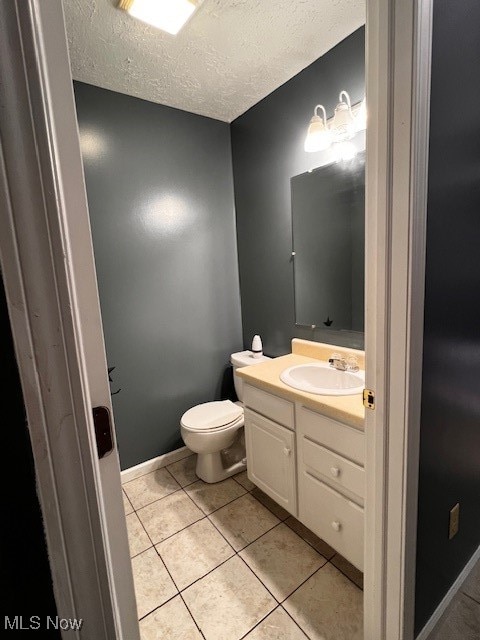 bathroom featuring vanity, tile patterned flooring, toilet, and a textured ceiling