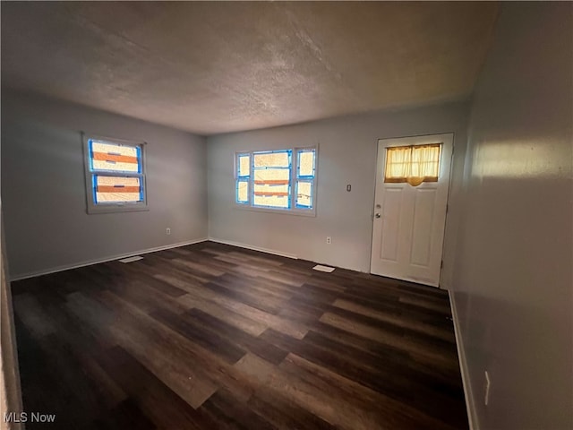 foyer entrance with dark hardwood / wood-style floors and a textured ceiling