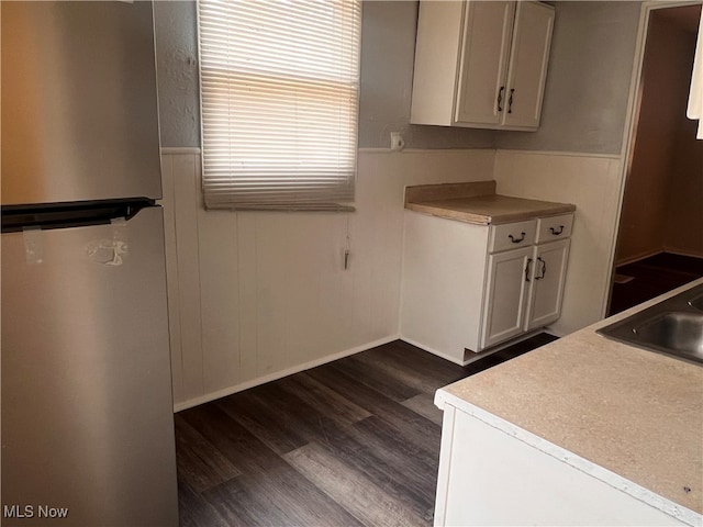 kitchen with dark wood-type flooring, white cabinetry, sink, and stainless steel fridge