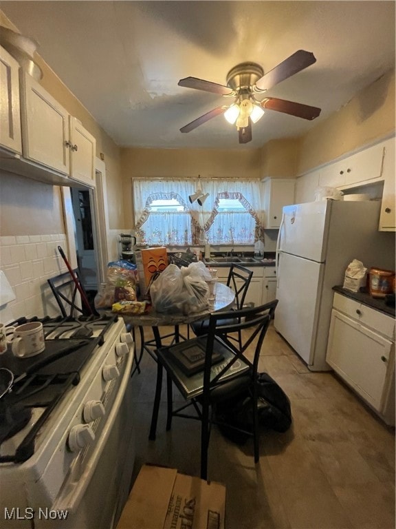 kitchen featuring stainless steel stove, decorative backsplash, white cabinets, and white refrigerator