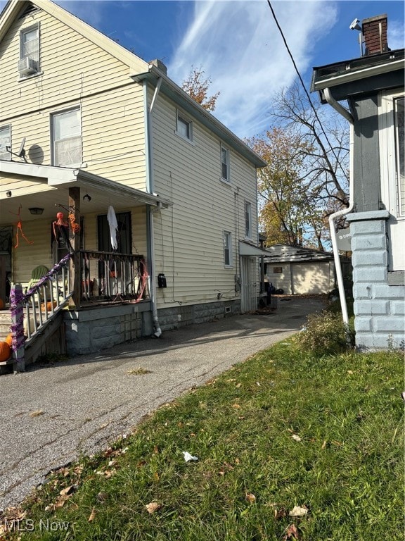 rear view of house with a porch, cooling unit, and a lawn