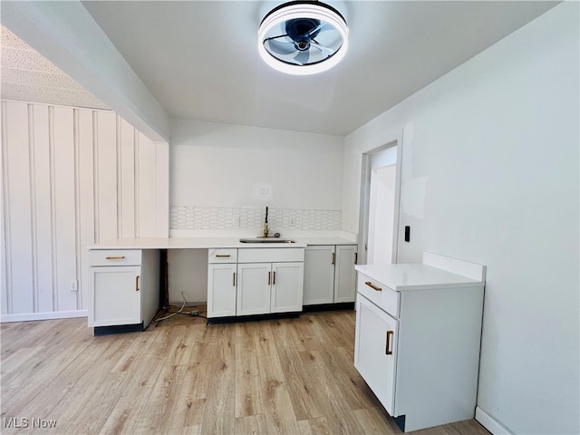 kitchen with white cabinetry, light hardwood / wood-style flooring, sink, and tasteful backsplash