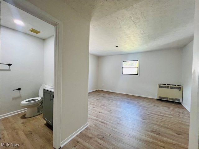 bathroom with hardwood / wood-style floors, heating unit, and toilet