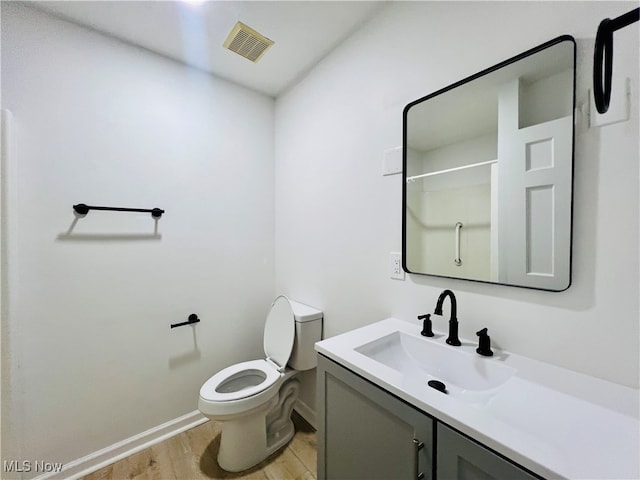 bathroom with walk in shower, wood-type flooring, toilet, and vanity