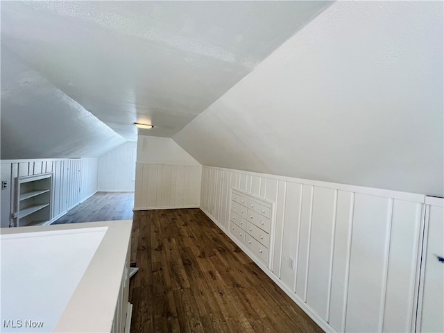 additional living space with a textured ceiling, dark hardwood / wood-style floors, and vaulted ceiling