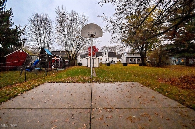 exterior space featuring a storage unit, a playground, and basketball hoop