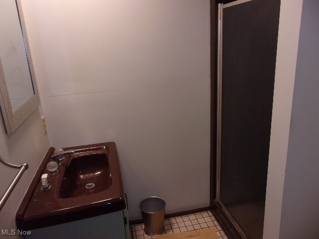 bathroom with walk in shower, vanity, and tile patterned flooring