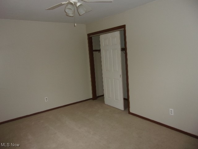 unfurnished bedroom with light carpet, ceiling fan, and a closet