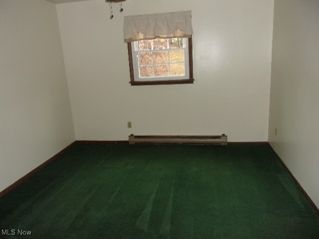 spare room with dark colored carpet and a baseboard heating unit