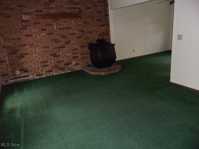 interior space featuring a wood stove, carpet floors, and brick wall