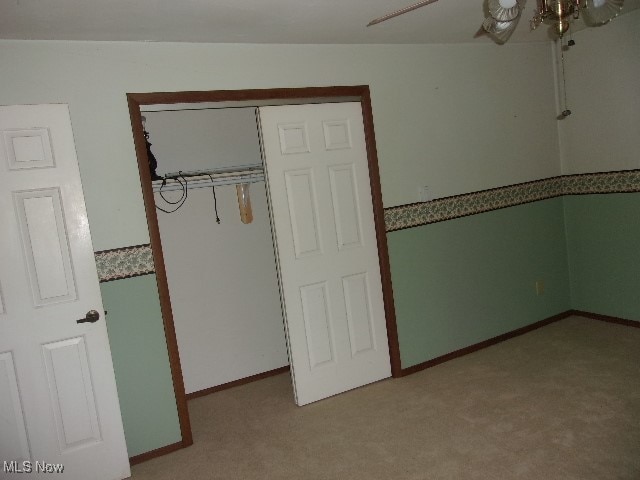 unfurnished bedroom with a closet, ceiling fan, and carpet floors