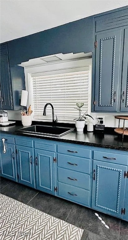 kitchen with blue cabinetry, sink, and dark tile patterned flooring