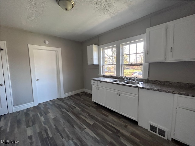 kitchen with dark wood-type flooring, a textured ceiling, sink, and white cabinets