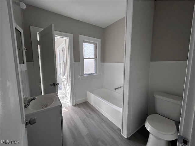 bathroom featuring toilet, vanity, hardwood / wood-style floors, and a bathing tub