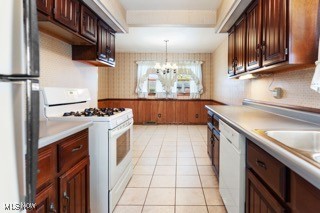 kitchen with pendant lighting, white appliances, light tile patterned floors, and a chandelier