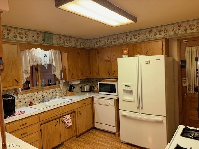 kitchen featuring light hardwood / wood-style flooring, tasteful backsplash, sink, and white appliances