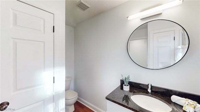 bathroom featuring toilet, vanity, a textured ceiling, and hardwood / wood-style flooring