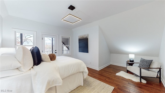 bedroom with dark hardwood / wood-style floors, access to exterior, and vaulted ceiling