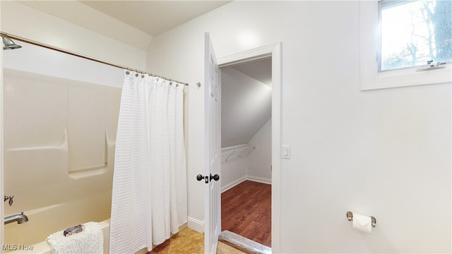 bathroom with wood-type flooring, lofted ceiling, and shower / tub combo with curtain