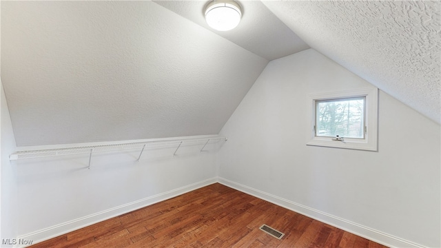 additional living space featuring hardwood / wood-style floors, a textured ceiling, and vaulted ceiling