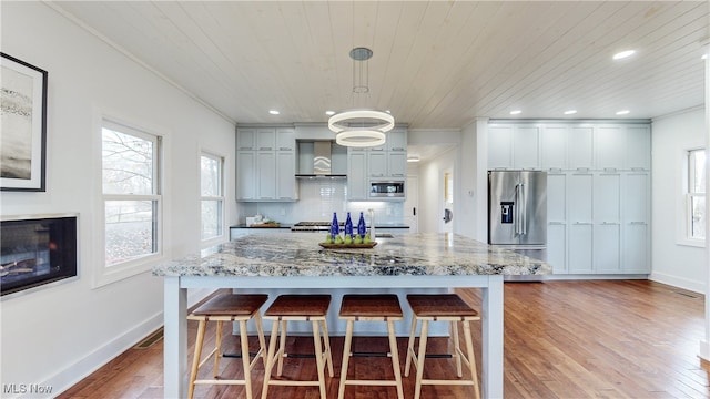 kitchen featuring gray cabinets, appliances with stainless steel finishes, decorative light fixtures, and light hardwood / wood-style floors