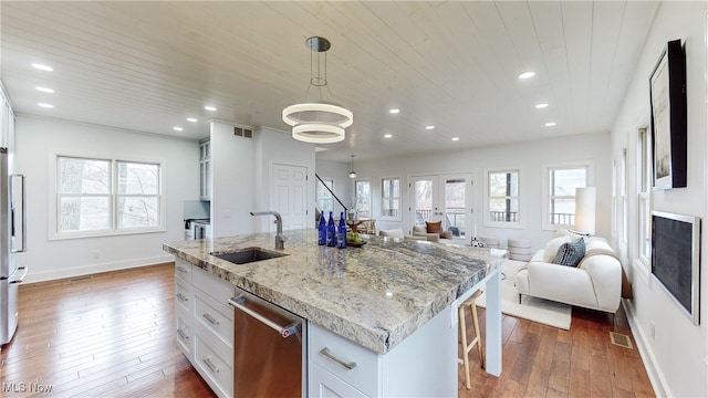 kitchen featuring white cabinets, wood-type flooring, sink, and an island with sink