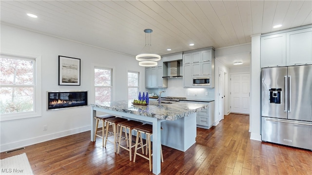 kitchen with light stone counters, a breakfast bar area, gray cabinetry, appliances with stainless steel finishes, and decorative light fixtures