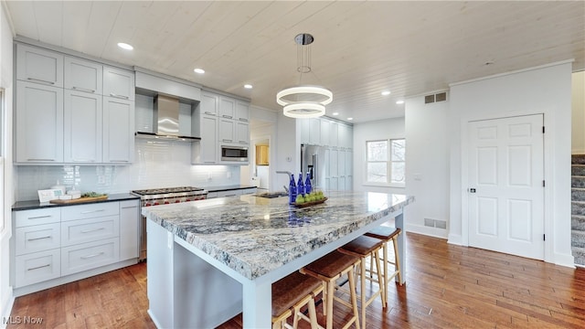 kitchen featuring hardwood / wood-style flooring, high end appliances, and a kitchen island with sink