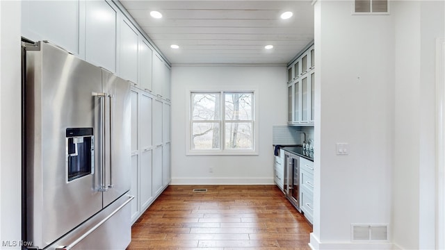 kitchen with white cabinets, dark wood-type flooring, tasteful backsplash, and high end refrigerator