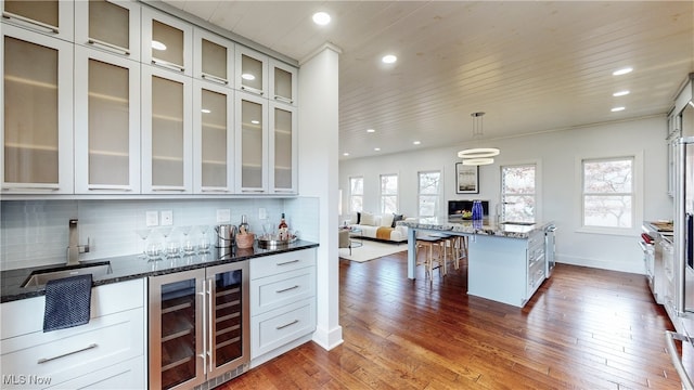 kitchen with dark hardwood / wood-style flooring, hanging light fixtures, dark stone counters, and backsplash