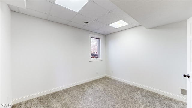 carpeted empty room featuring a paneled ceiling