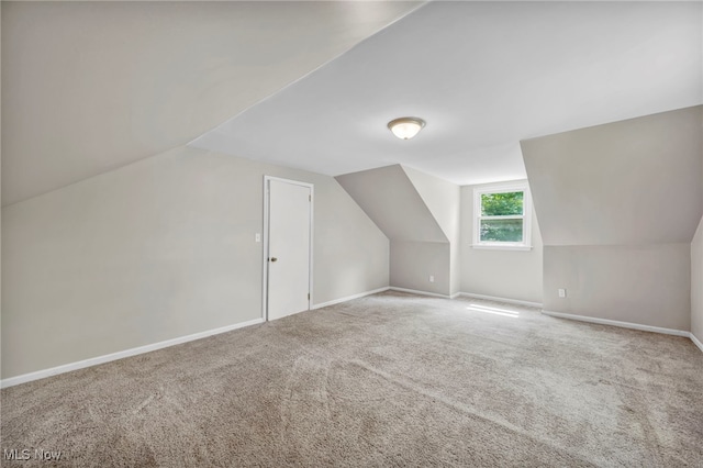 additional living space featuring lofted ceiling and carpet flooring