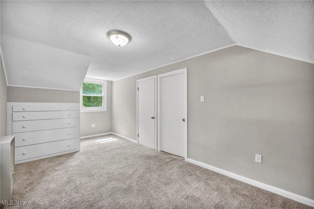 bonus room featuring vaulted ceiling, light carpet, and a textured ceiling