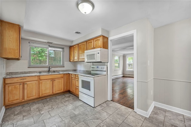 kitchen with light wood-type flooring, white appliances, sink, and a healthy amount of sunlight