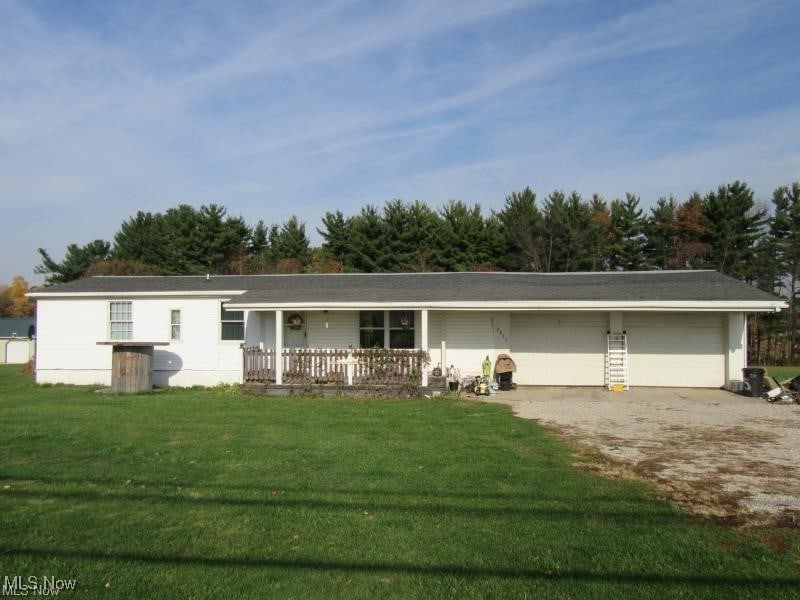 ranch-style home featuring a garage, a front yard, and covered porch