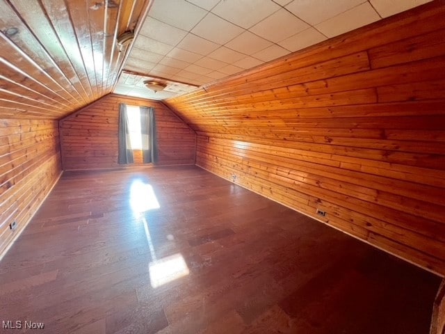 additional living space featuring wooden walls, vaulted ceiling, and dark hardwood / wood-style floors