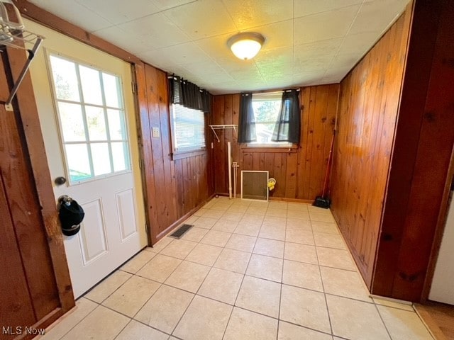 doorway to outside featuring wooden walls and light tile patterned floors