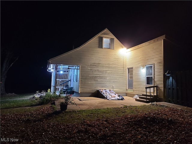 back house at night featuring a patio