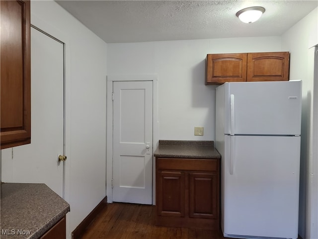 kitchen featuring dark wood-type flooring, a textured ceiling, and white fridge