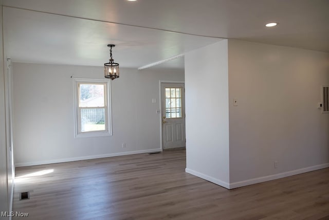 unfurnished room featuring an inviting chandelier and light wood-type flooring