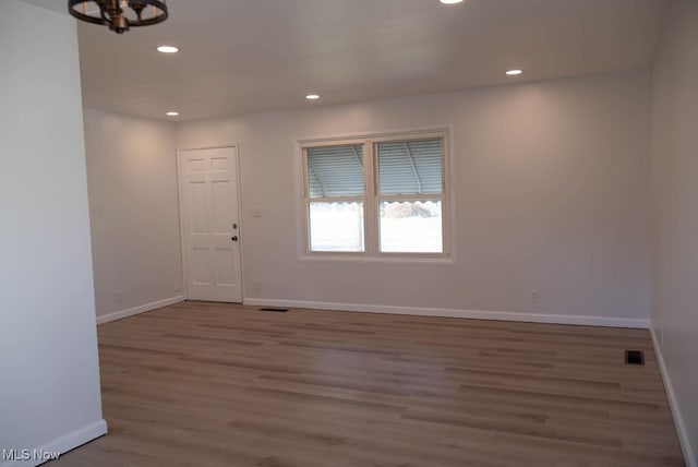 empty room with hardwood / wood-style flooring and an inviting chandelier