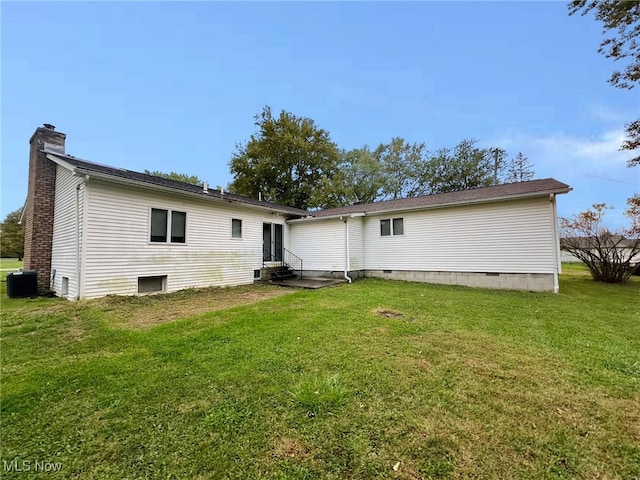 rear view of house with central AC and a yard