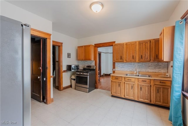 3594 W 49th St, Cleveland, OH 44102 - kitchen featuring stainless steel appliances, decorative backsplash, light countertops, a sink, and brown cabinets