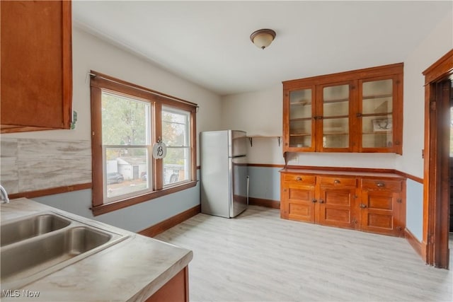 3594 W 49th St, Cleveland, OH 44102 - kitchen featuring freestanding refrigerator, a sink, light wood finished floors, brown cabinets, and glass insert cabinets