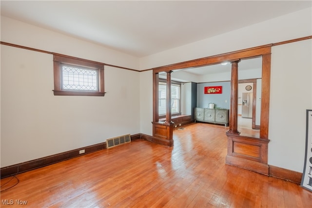 empty room featuring ornate columns and hardwood / wood-style flooring