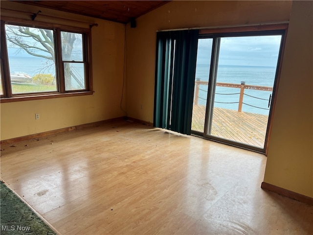 unfurnished room with light hardwood / wood-style flooring, a water view, lofted ceiling, and wooden ceiling