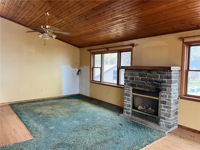 unfurnished living room with hardwood / wood-style flooring, a stone fireplace, a healthy amount of sunlight, and wood ceiling