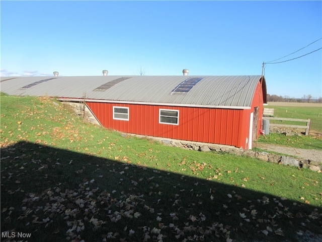 view of side of property with a rural view, a yard, and an outdoor structure