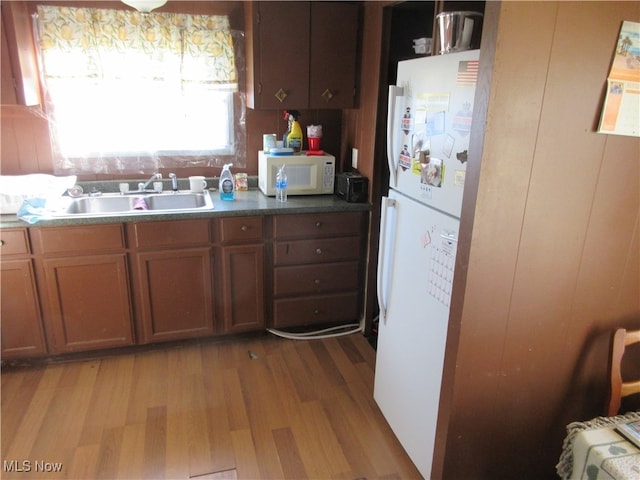 kitchen with light wood-type flooring, sink, and white appliances