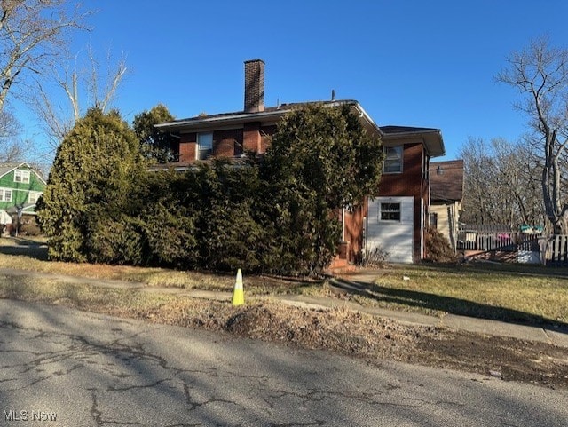 view of home's exterior featuring a chimney and fence